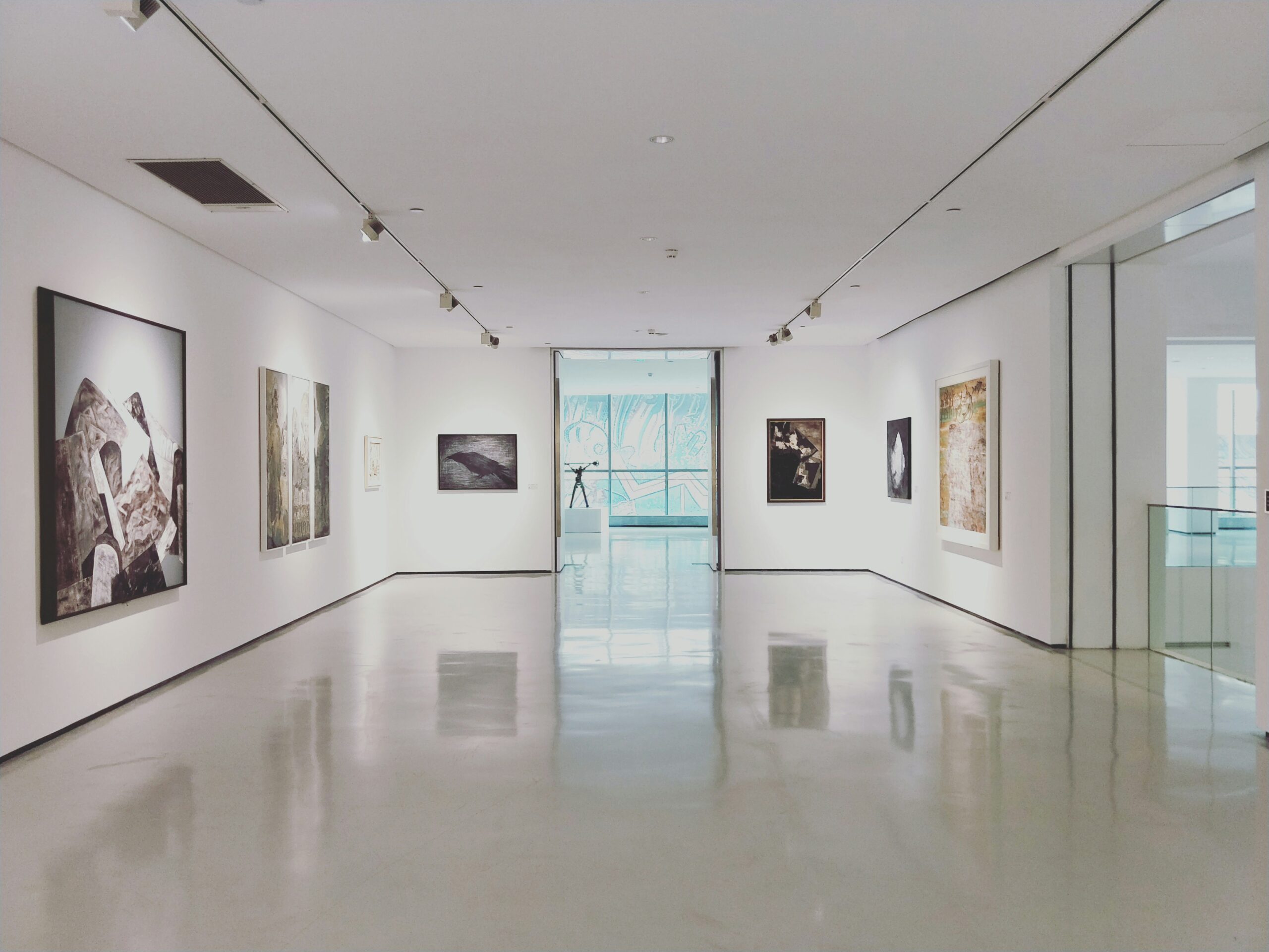 Sala museo con pavimento in micro-cemento bianco, pareti bianche e quadri colorati contemporanei
