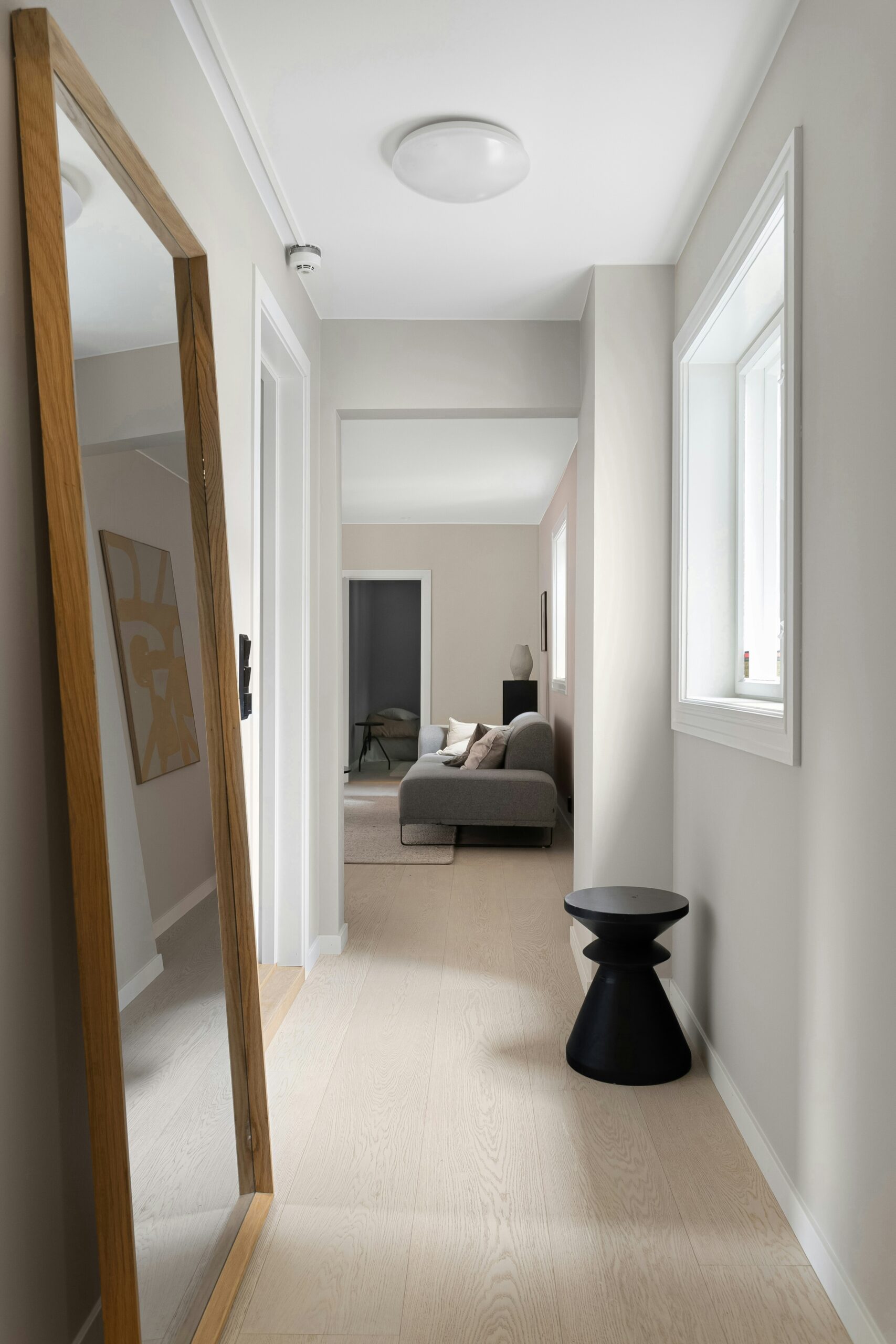 corridoio in stile nordico con parquet in rovere schiarito, pareti bianche e grande specchio a parete