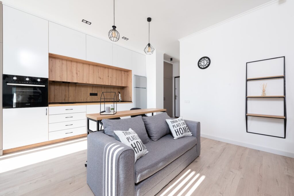 cucina lineare bianca con top in legno massello di rovere e divano due posti grigio